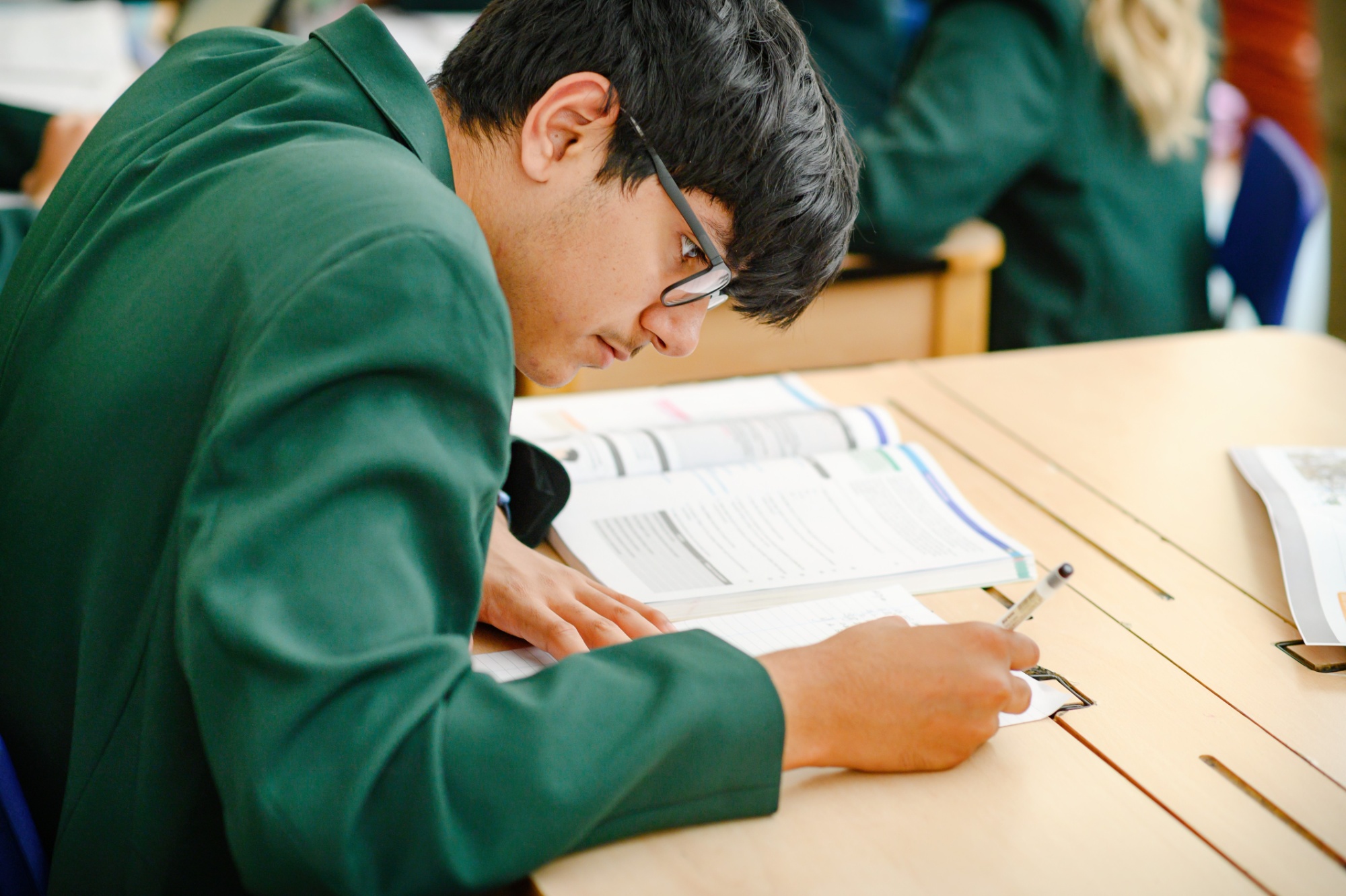 A male student writes in an exercise book.